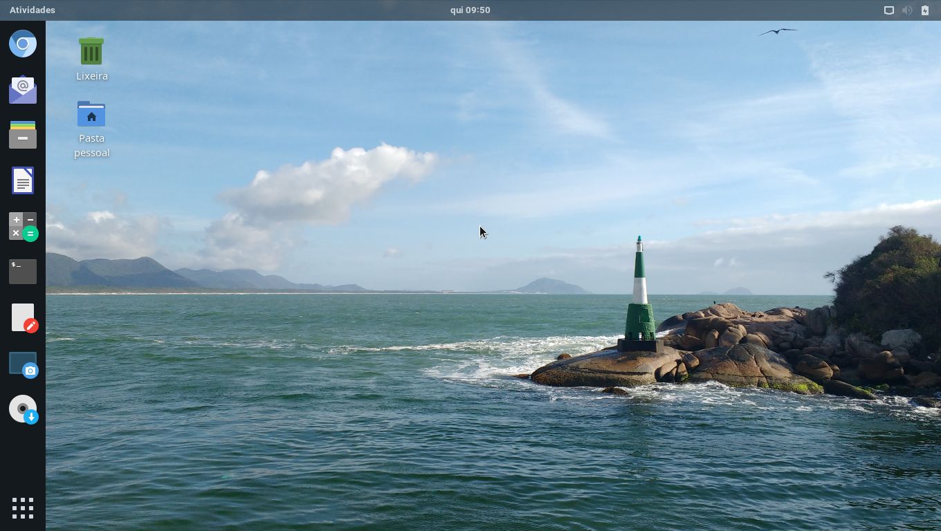 Área de trabalho do Linux Kamarada. O plano de fundo é uma foto da belíssima praia da [Barra da Lagoa](https://goo.gl/maps/CLygYshBfm12i3TY8), em [Florianópolis (SC)](https://pt.wikipedia.org/wiki/Florianópolis).